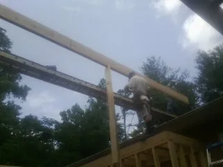 Carpenter setting a ridge beam over a new addition frame — Ice Dam Removal by Roofing Brothers in Glen Allen