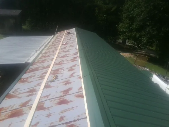 Old rusted panels beside newly installed green metal roofing — Wind Damage Roof Repair by Roofing Brothers in Glen Allen