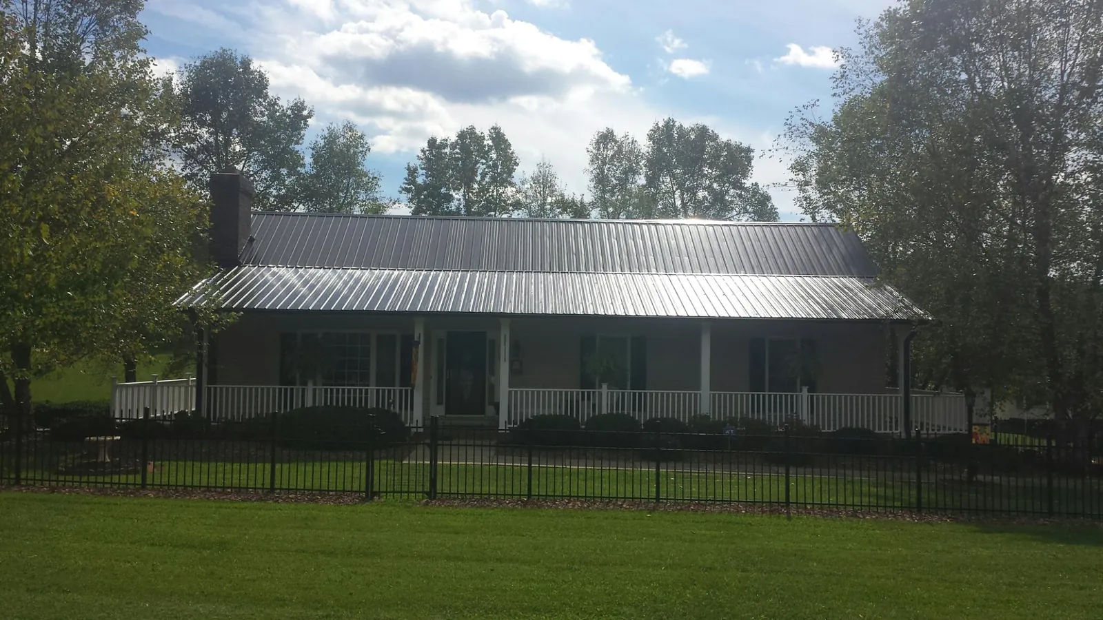 Gray metal roof on a brick ranch with a full width front porch — Gutter Guard Installation work by our crew in Glen Allen